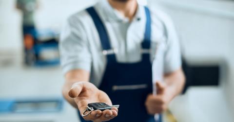 Auto repair technician holds a car key fob out in his palm