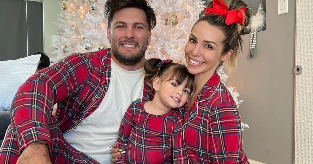 Brock Davies, Scheana Shay, and their daughter in front of a Christmas tree