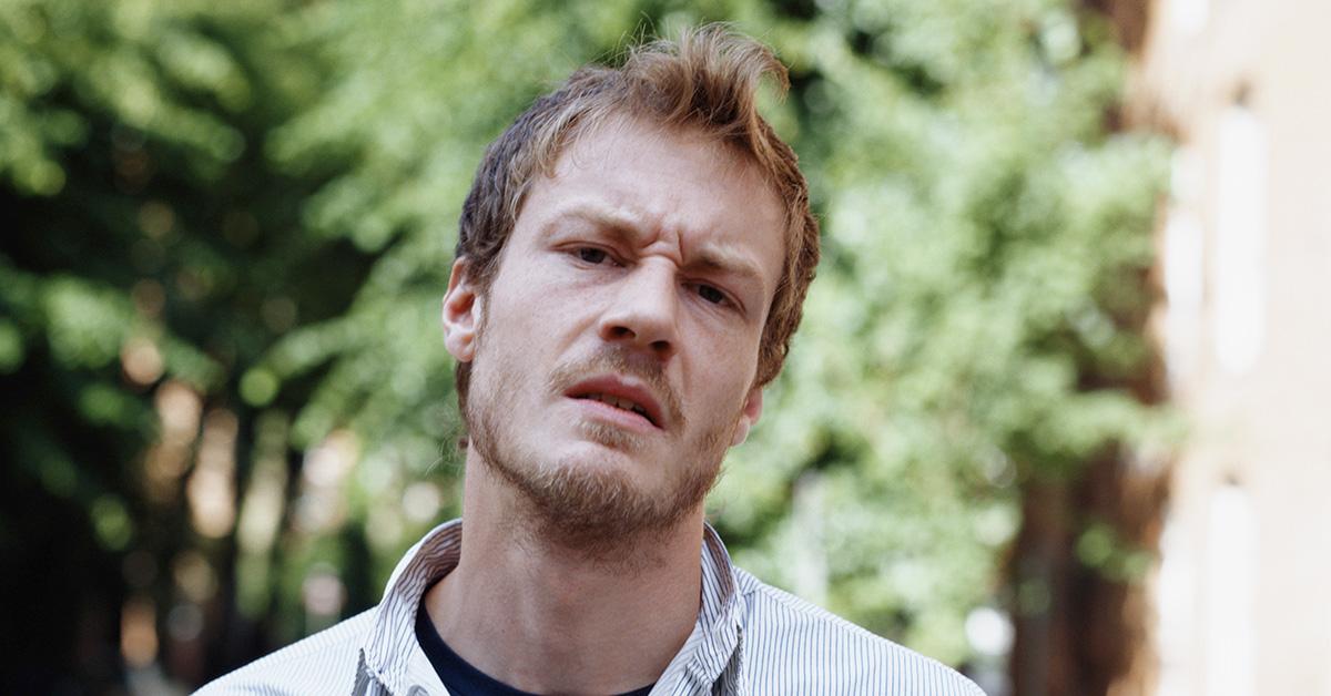 A man in a button down shirt looking frustrated. 