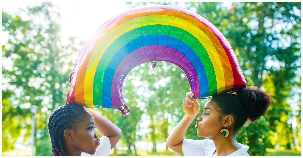 Two women holding a rainbow balloon.