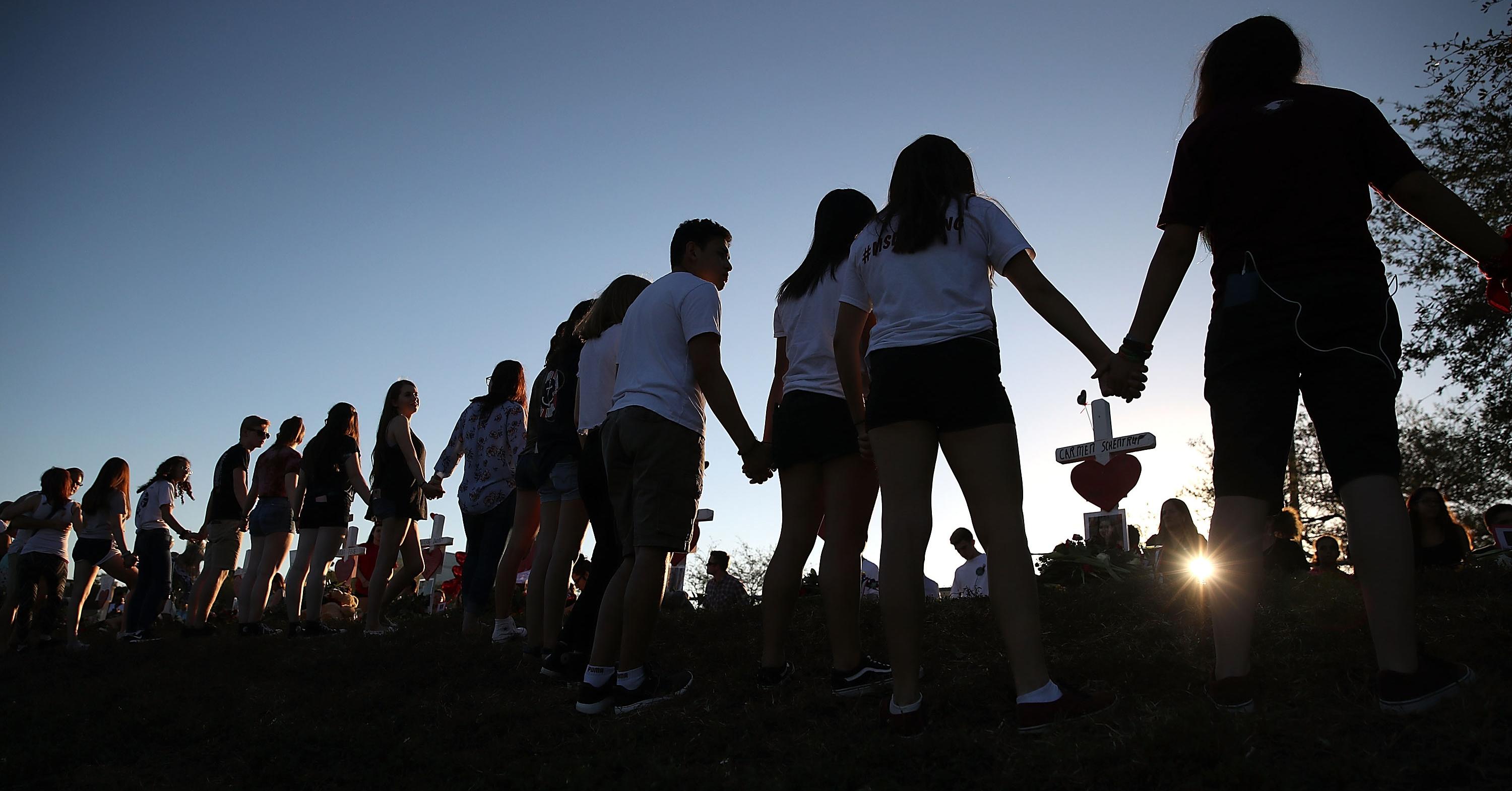 People hold hands at a Parkland High School shooting vigil