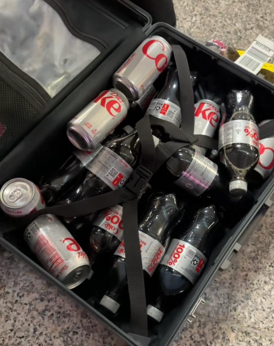 A woman's suitcase packed full of Diet Coke cans and bottles