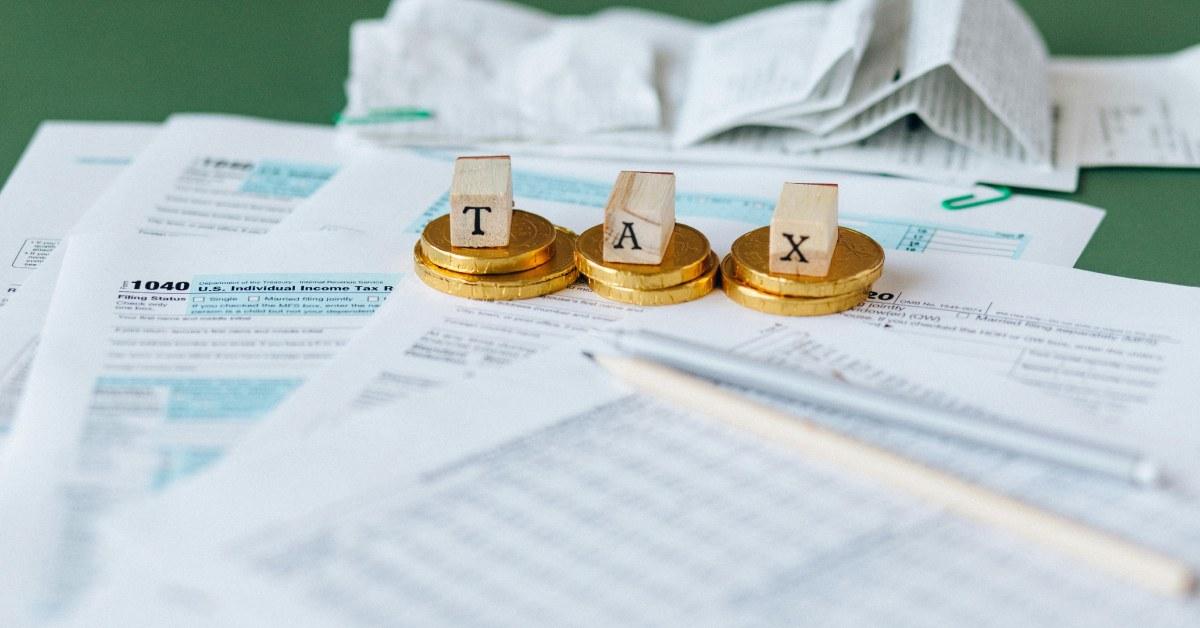 Tax spelled out with tax forms in the background.