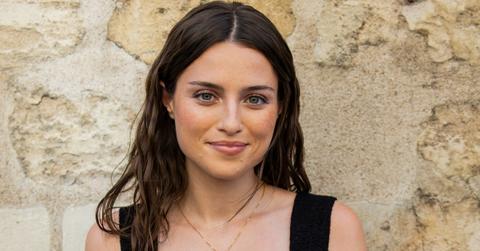 Madeline Argy wears black dress, white bag outside Patou during the Haute Couture Fall/Winter show.