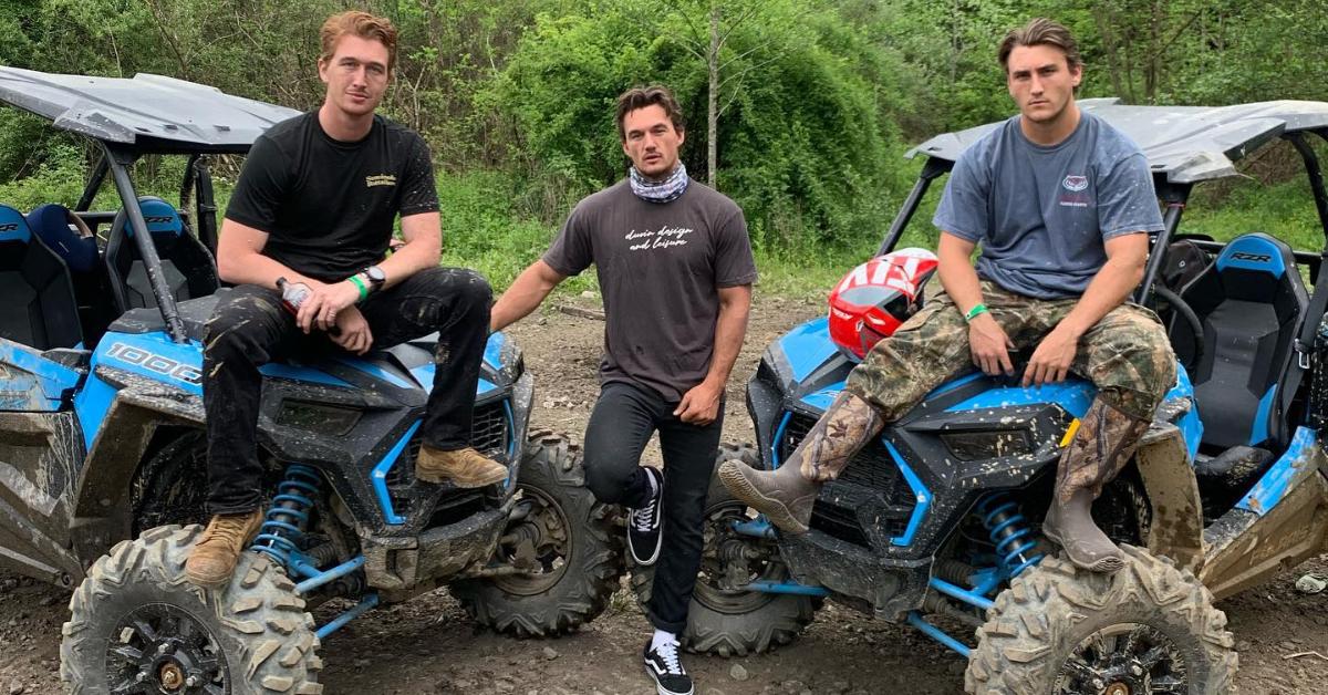 Tyler Cameron (center) stands as his brothers, Austin (left), and Ryan (right), sit on the hood of ATV quad bikes.