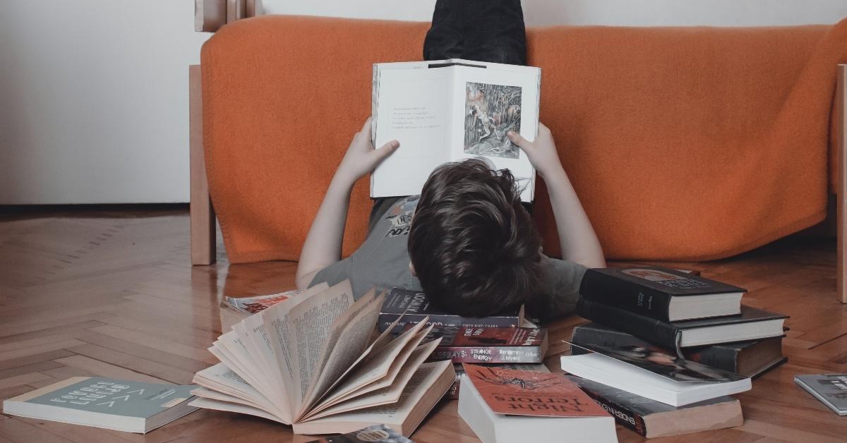 A boy reading books on the floor