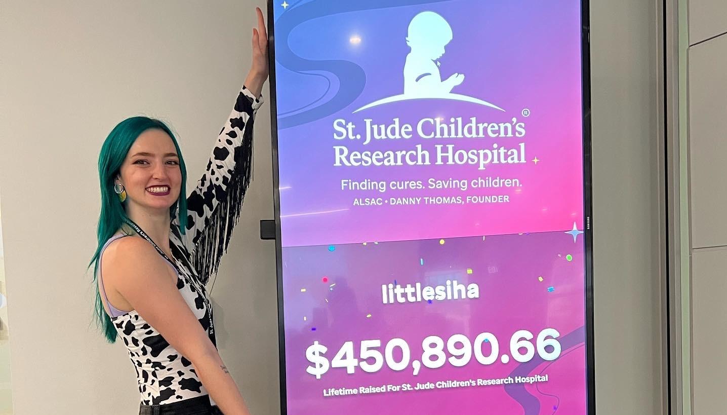 LittleSiha standing in front of her lifetime donations to St. Judes Hospital