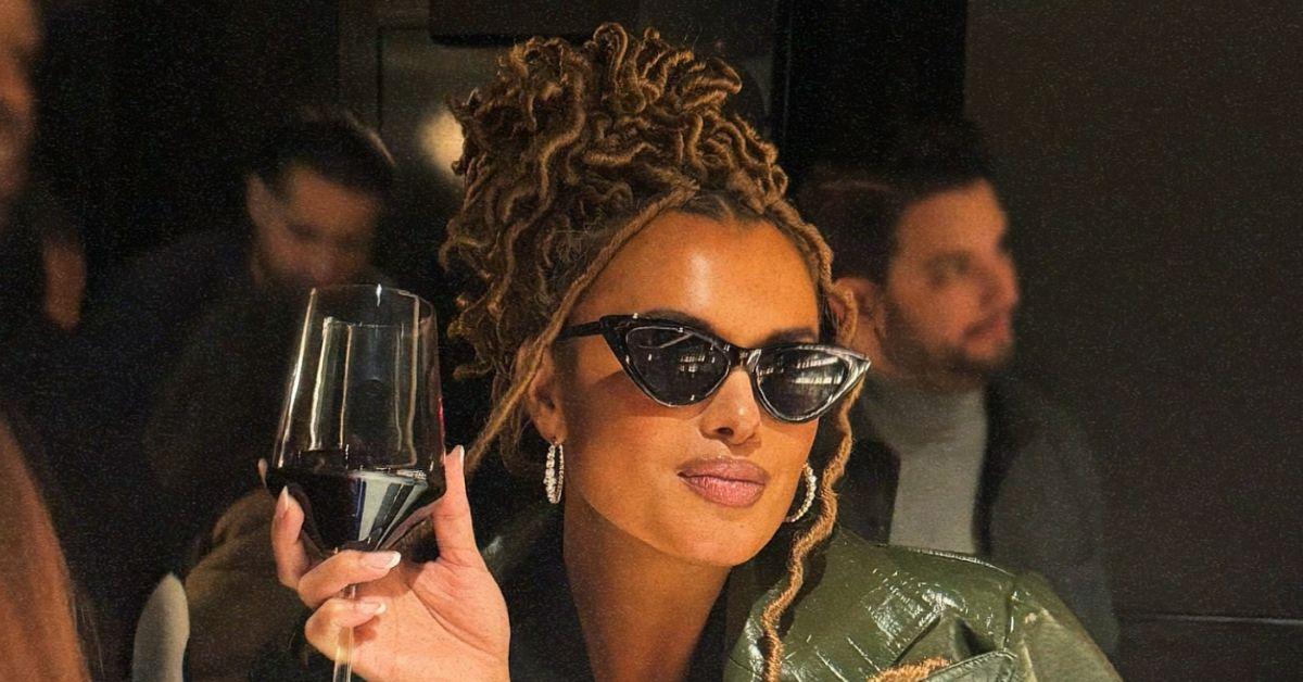 Joy Taylor wearing sunglasses holding a wine glass. 