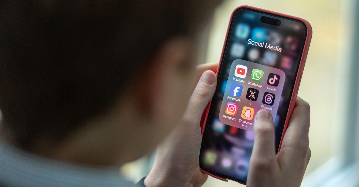 Boy holding phone as he looks at a selection of social media apps