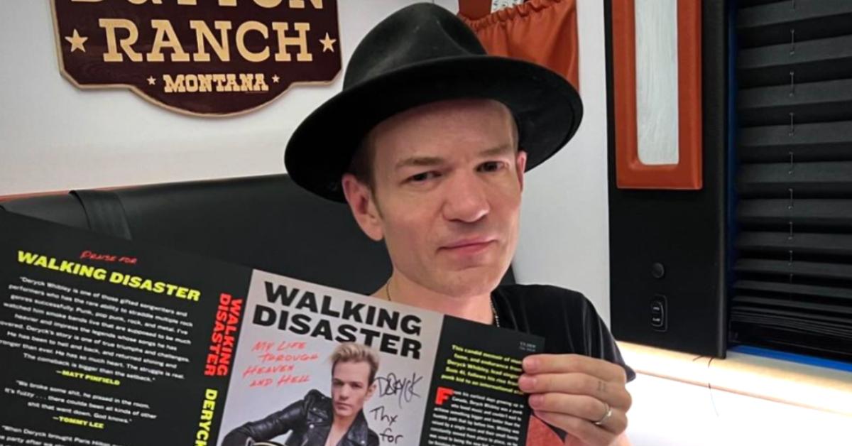 Sum 41 singer Deryck Whibley holds up an autographed copy of his memoir