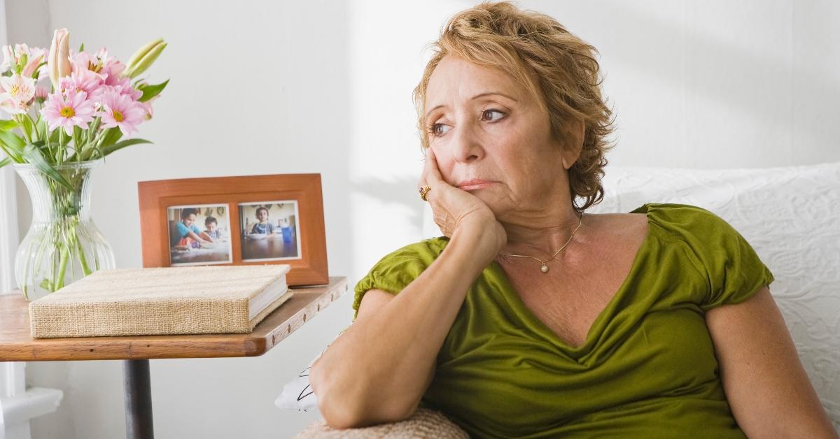 A woman appears to be sad, sitting on a couch.