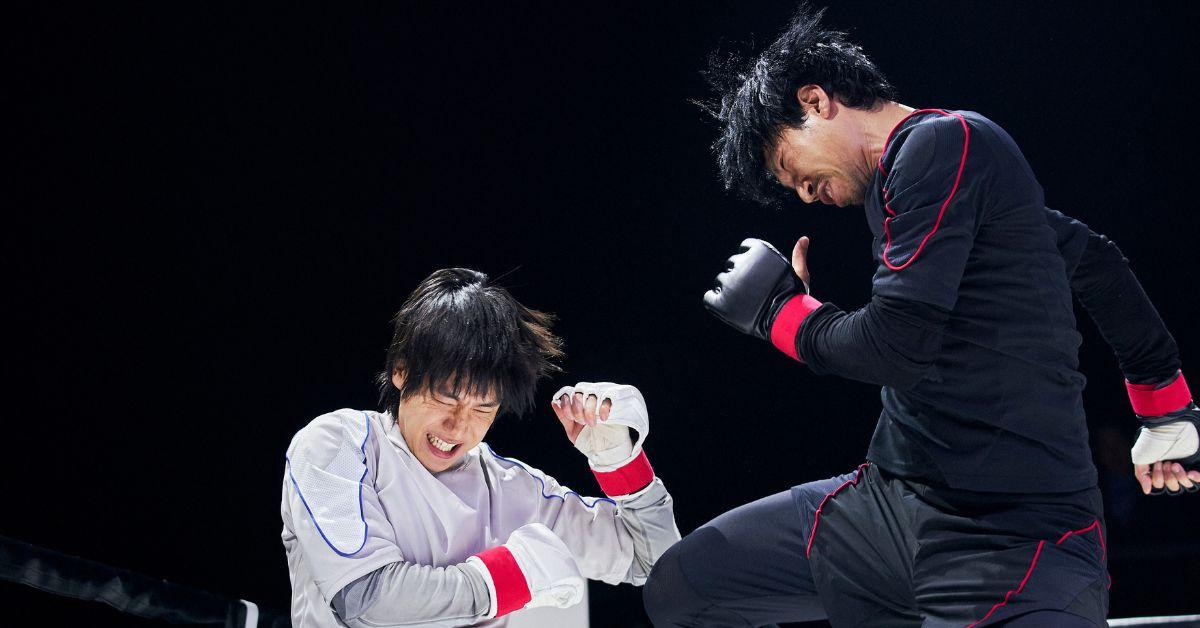 (l-r): Two people fighting in white and black uniforms and boxing gloves.