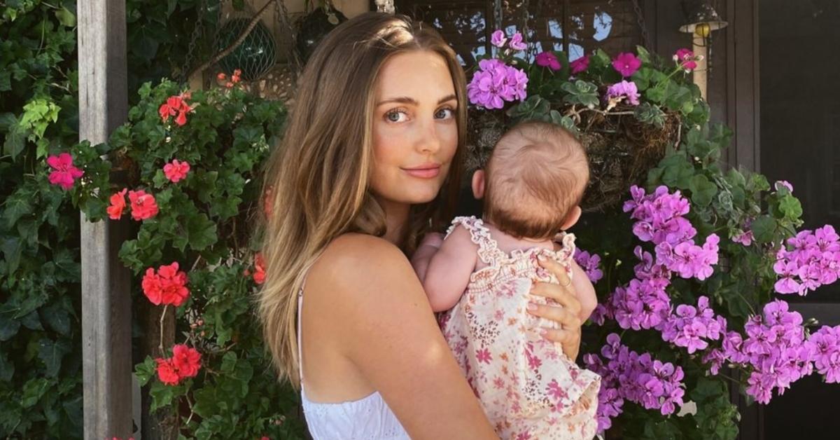 Asypn Ovard holding third child, baby girl, in front of flowers