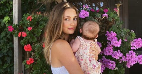 Asypn Ovard holding third child, baby girl, in front of flowers