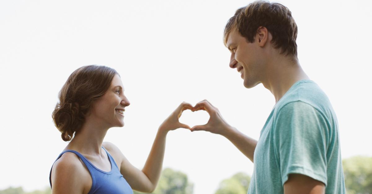 Cheesy couple making a heart with their hands