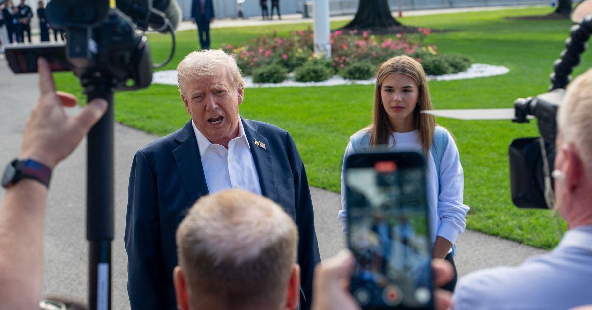 kai Trump stands beside Donald Trump as he talks to the press