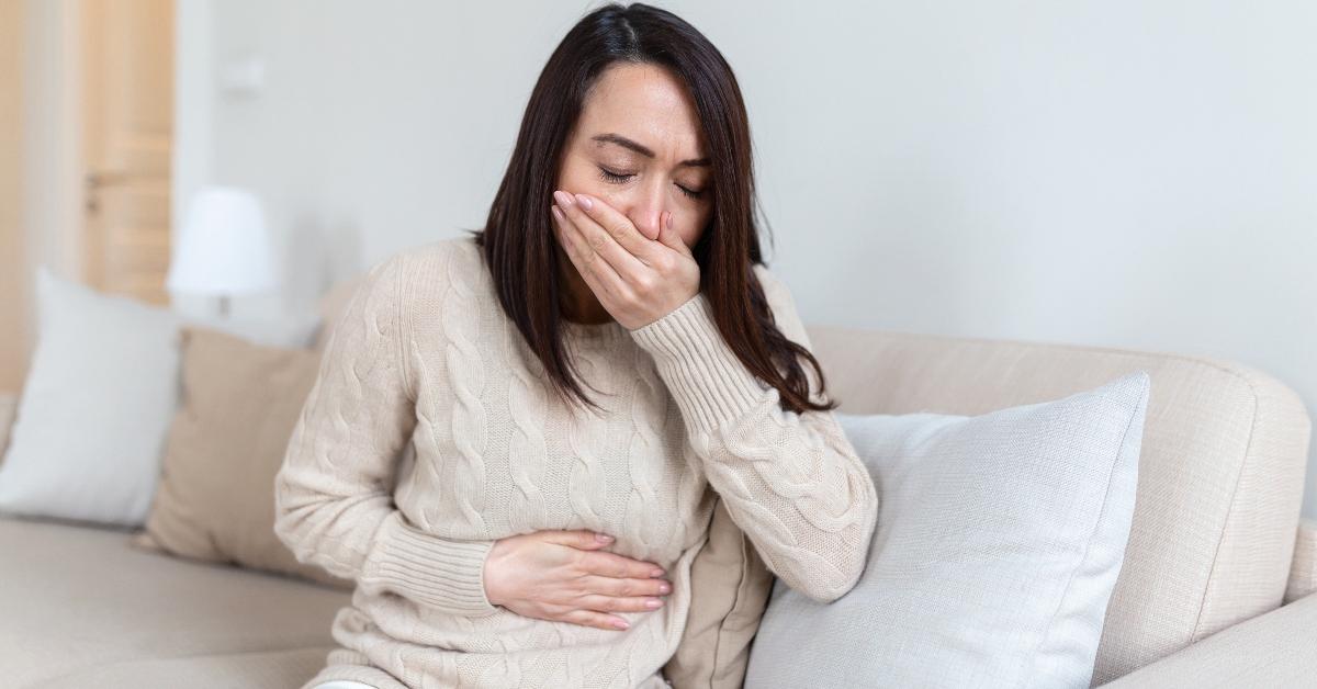 Woman with her hands over her stomach and mouth.