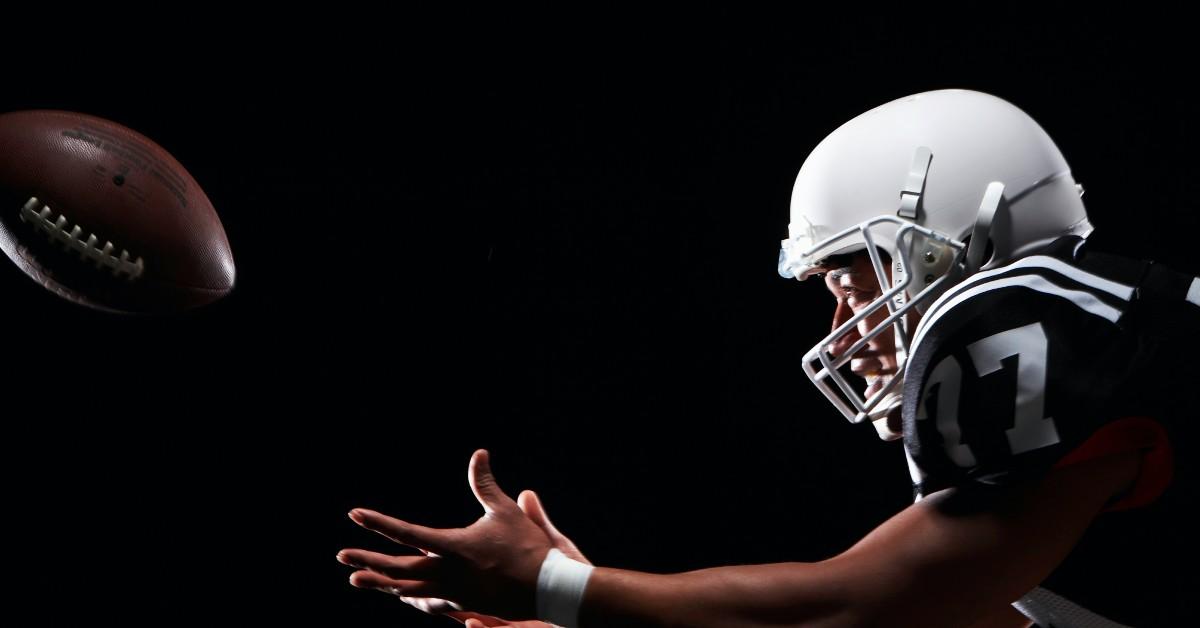 A football player attempts to catch the ball. 