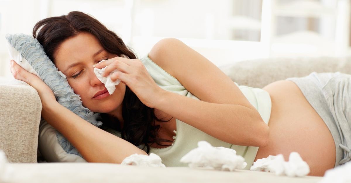 A pregnant woman crying on the couch