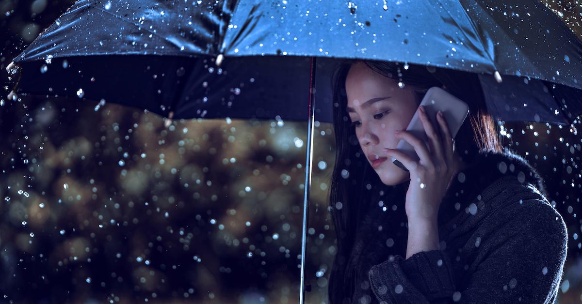 woman talking on phone in the rain, holding umbrella
