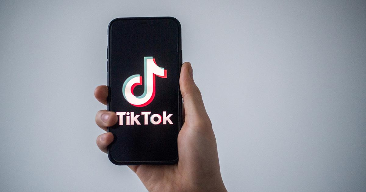 A hand holding a phone with the TikTok logo. 