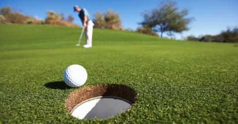 Male golfer putting on golf course - stock photo
