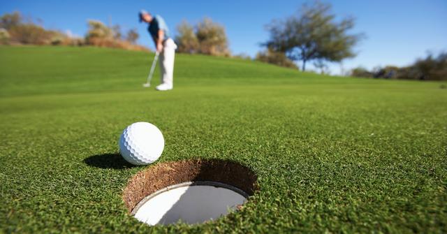 Male golfer putting on golf course - stock photo