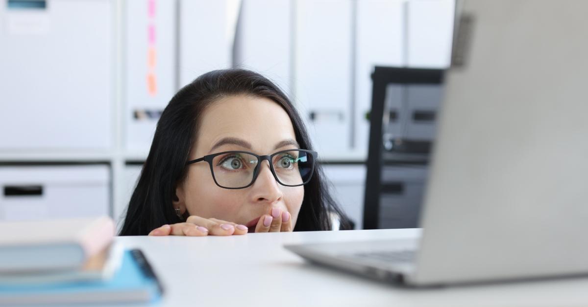 woman looks shocked by what is on her computer screen