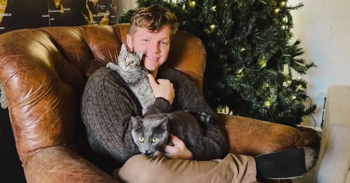 garrison brown sitting with his cats in front of christmas tree