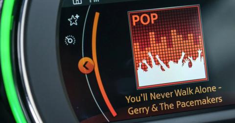 The song title "You'll Never Walk Alone" is shown on the display of a car radio.