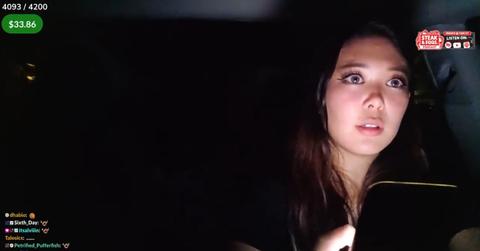 Streamer ExtraEmily driving while holding her phone and live streaming.