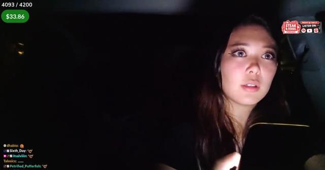Streamer ExtraEmily driving while holding her phone and live streaming.