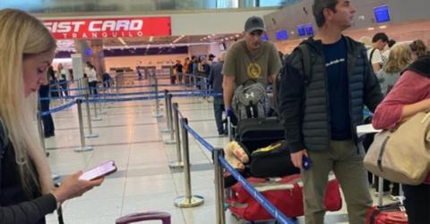 Woman at airport on her phone refuses to move her suitcases further up in the line.