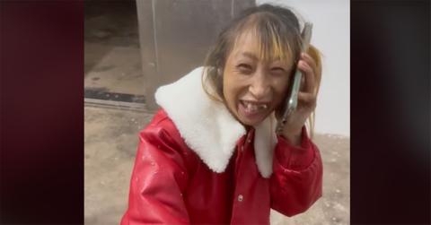 Xiao Xiao holding a phone to her face in a red jacket.