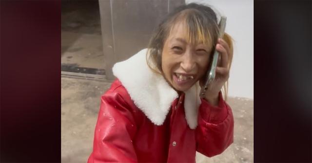 Xiao Xiao holding a phone to her face in a red jacket.