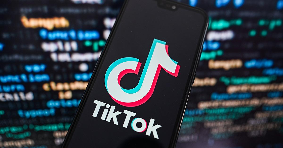 The TikTok logo against a blurry code background. 