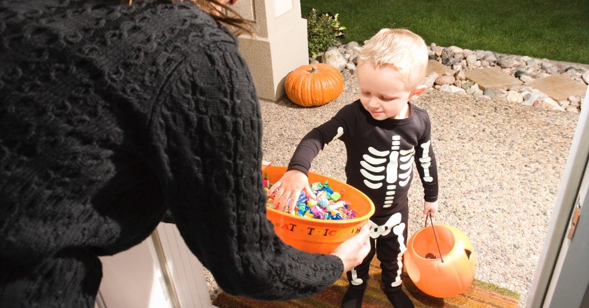 A child picking up candy during trick or treating on  Halloween.