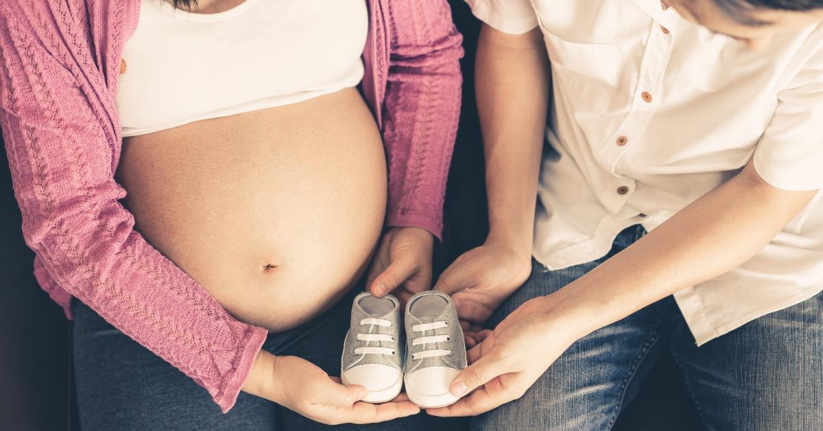 Pregnant couple holds baby shoes