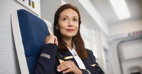 A flight attendant seated in a jump seat on a plane