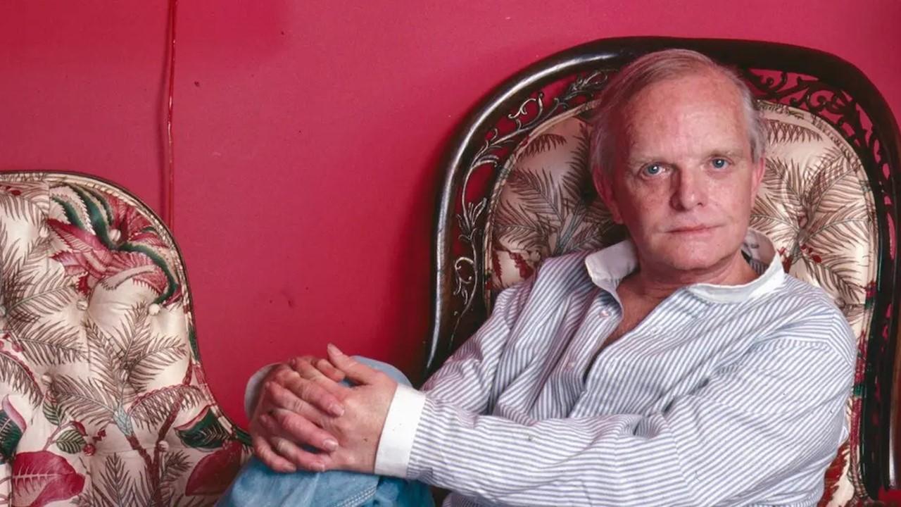 Truman Capote sitting in a chair in his United Nations Plaza residence in 1980