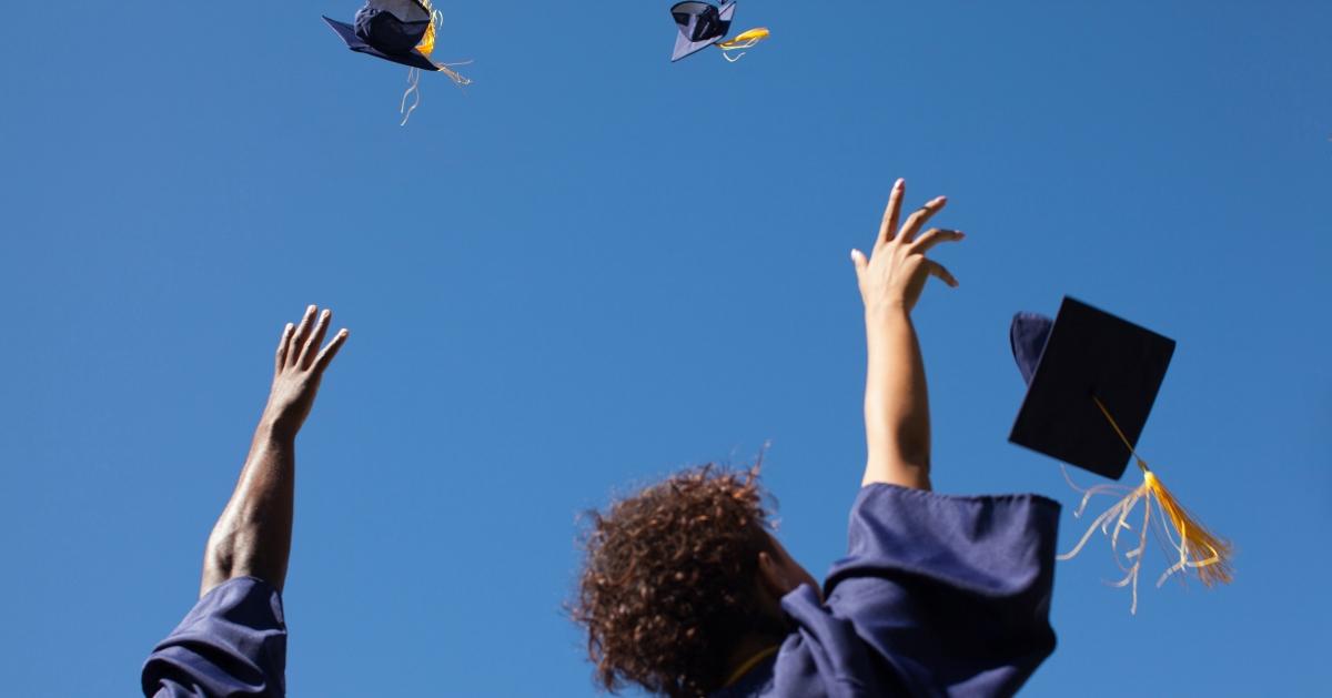 college graduates throwing their caps up in the air in celebration of graduating