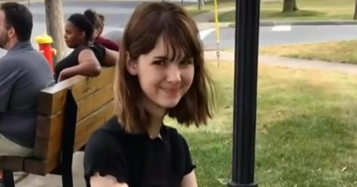 Bianca Devins smiles wearing a black top while sitting outside