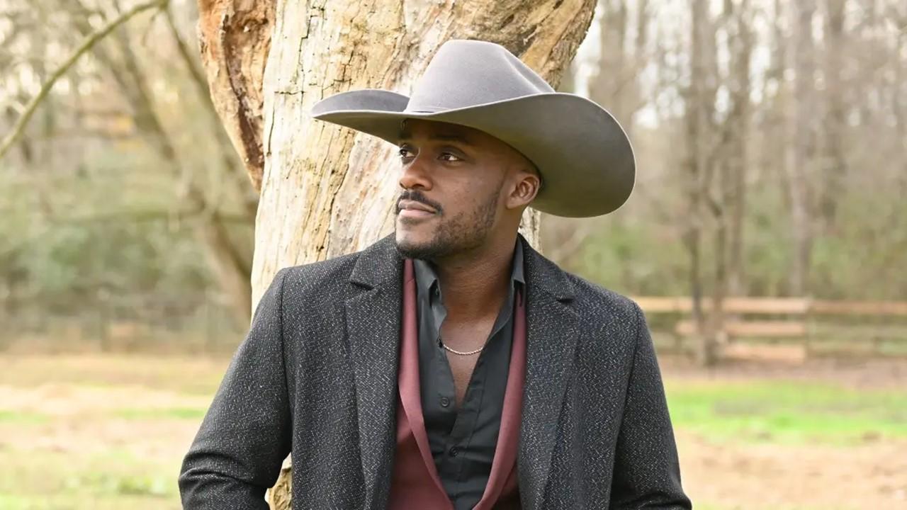 Ryan from 'Farmer Wants a Wife' looking pensive standing next to a tree wearing a cowboy hat