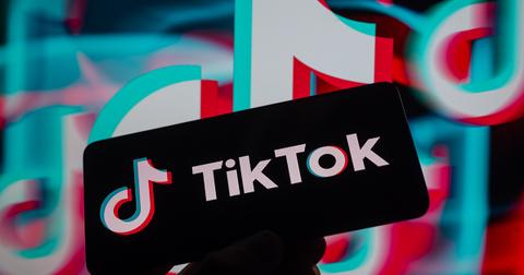 A TikTok logo on a screen with a logo behind it.