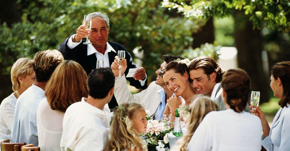 A father toasting his daughter on her wedding day surrounded by her wedding party.