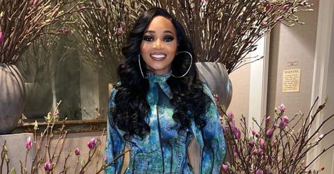 Leanne "LeLee" Lyons of SWV posing in a blue dress in front of pink flowers.