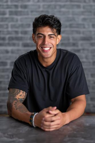 Tony is wearing a black t-shirt and smiling for his official portrait for Season 2 of 'The Mole.'