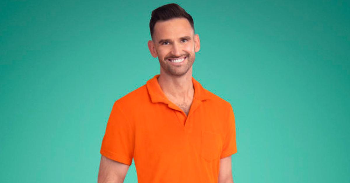 Carl Radke smiles and poses for Season 8 of 'Summer House' in a neon orange polo.