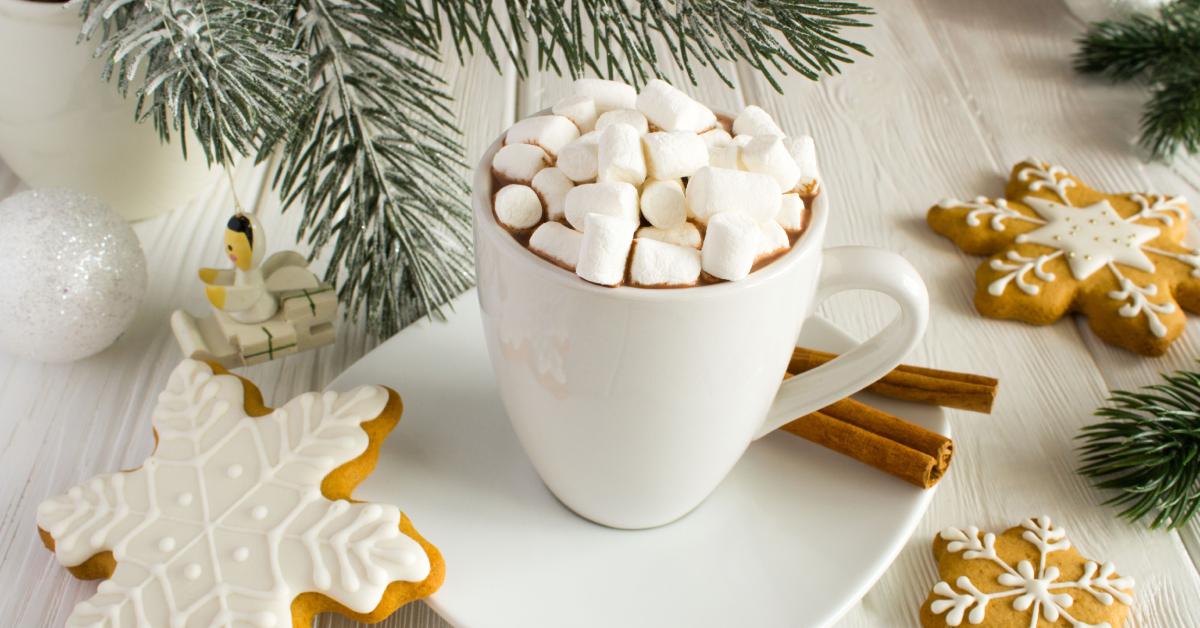 A mug of hot chocolate with marshmallows and holiday cookies 