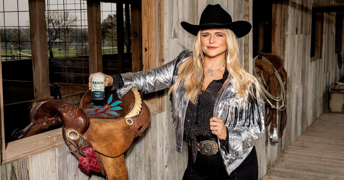 Miranda poses next to a saddle holding a can of Lone River's ranch water.